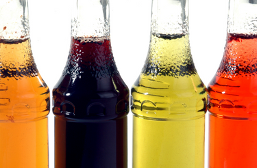 Clear glass bottles containing various colors of syrup