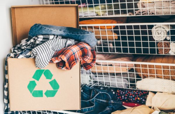 a box with a recycling symbol filled with clothes in a closet